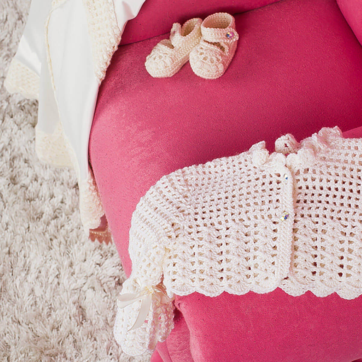 Pregnant belly with pink pants and Baby Keepsake Cardigan , accompanied by a pair of baby shoes.