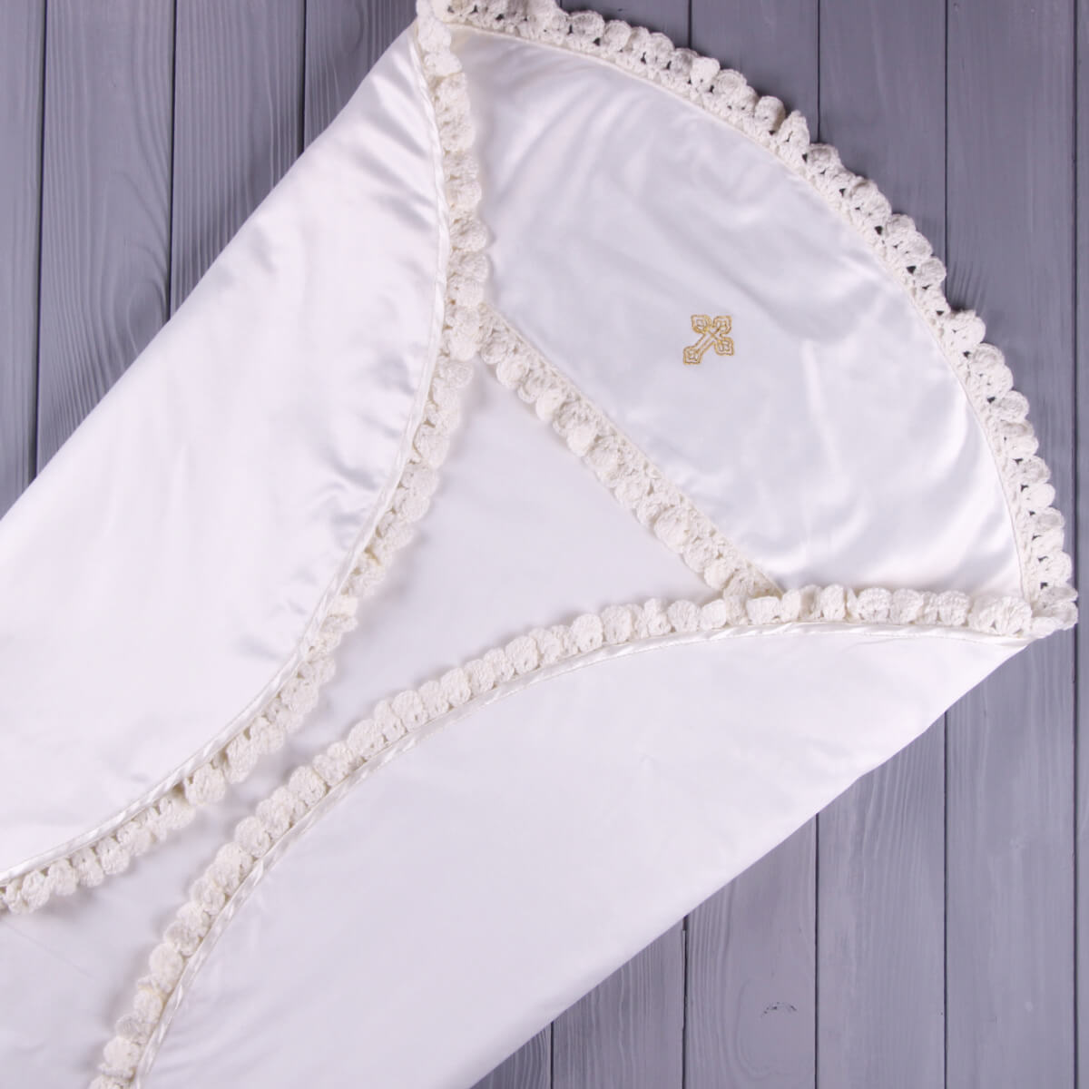 White baby blanket with lace trim on a wooden surface