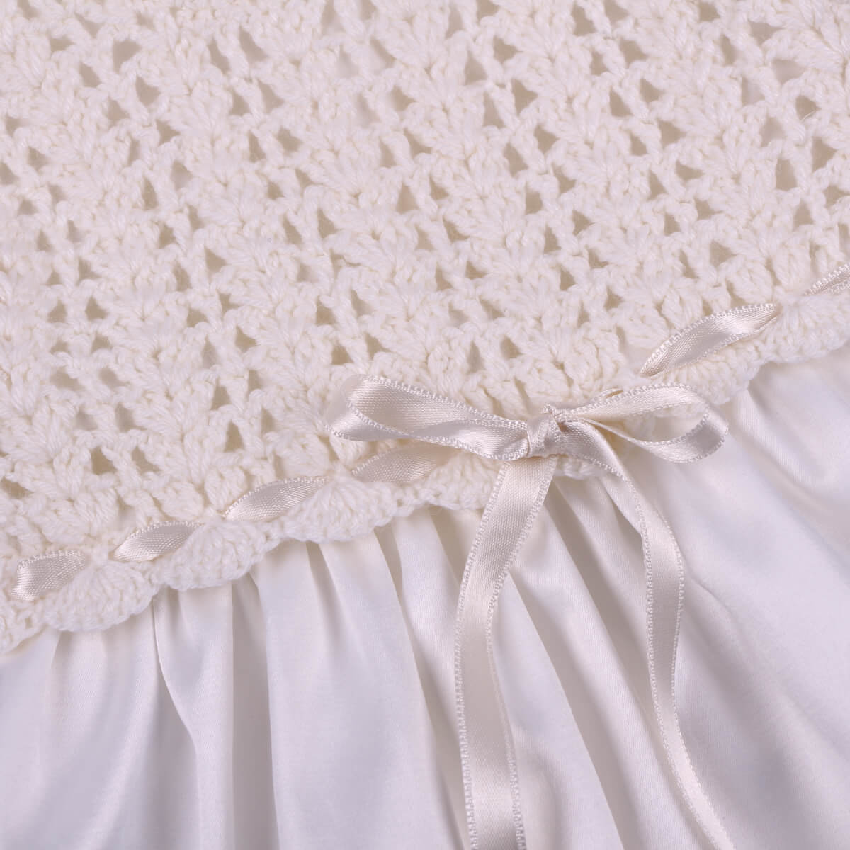 Close-up of a Christening Gown for Girls with a satin ribbon on a white background