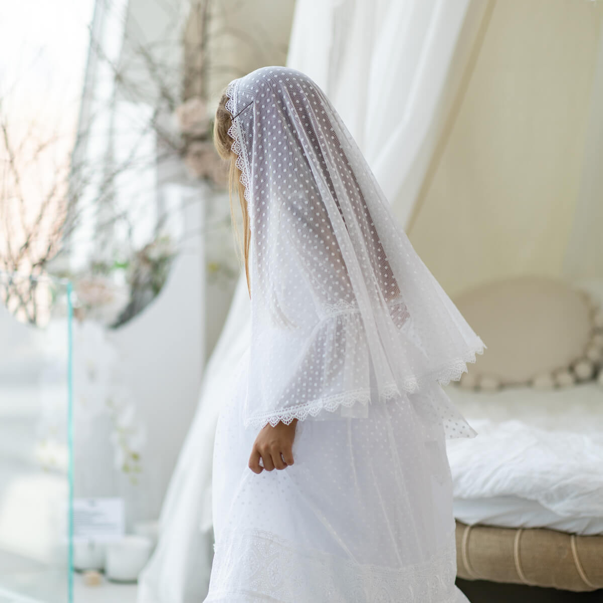 Person wearing a white polka dot veil in an outdoor setting