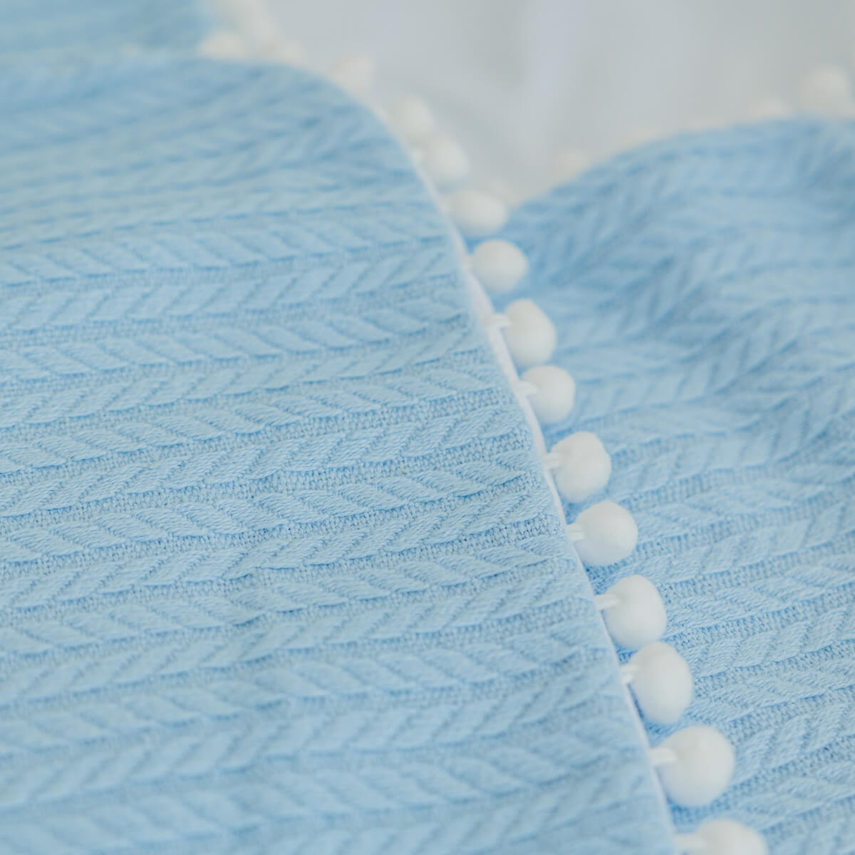 Close-up of Coming Home Blanket with white pom-pom trim
