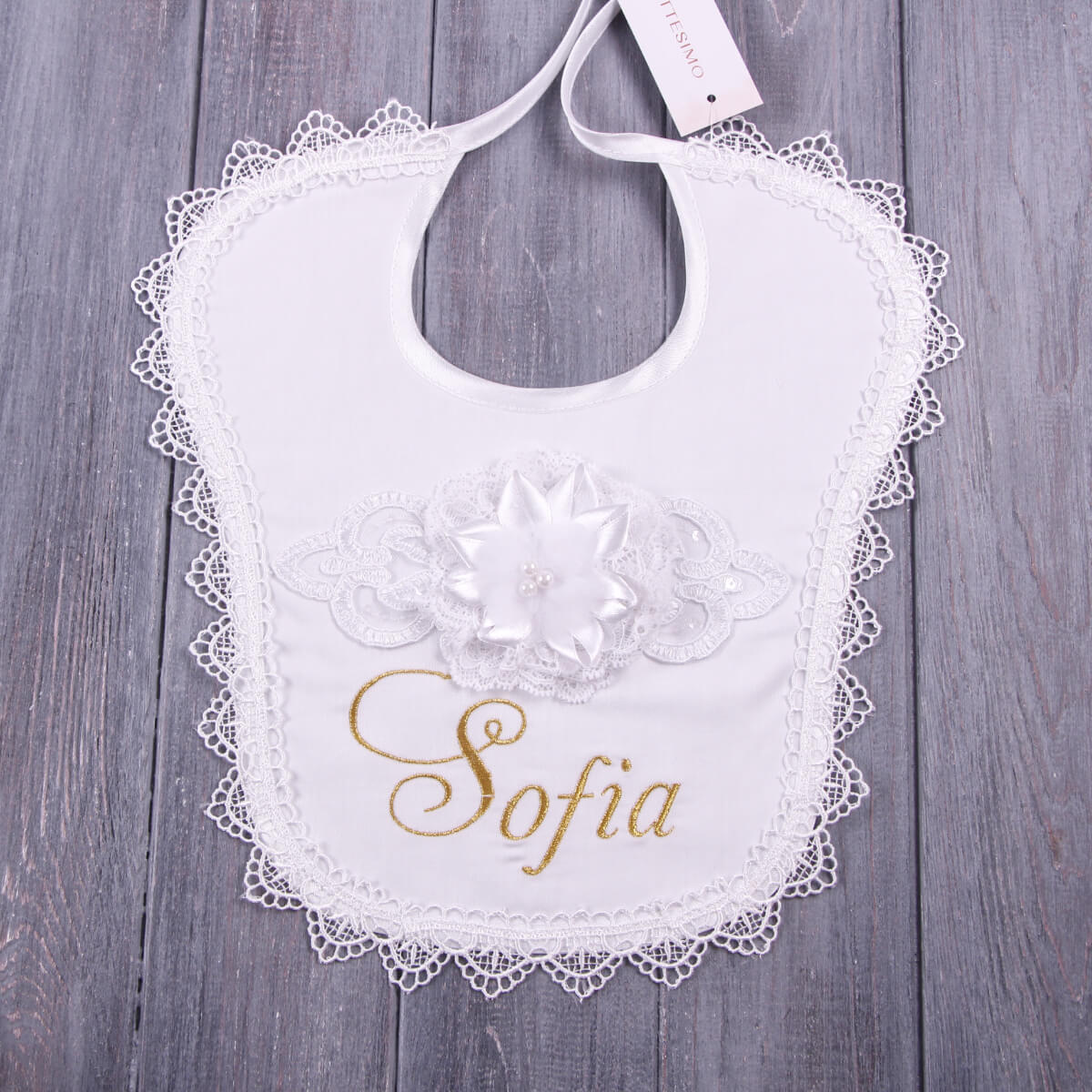 Baptism Bib with Floral Lace with 'Sofia' embroidered on a wooden surface