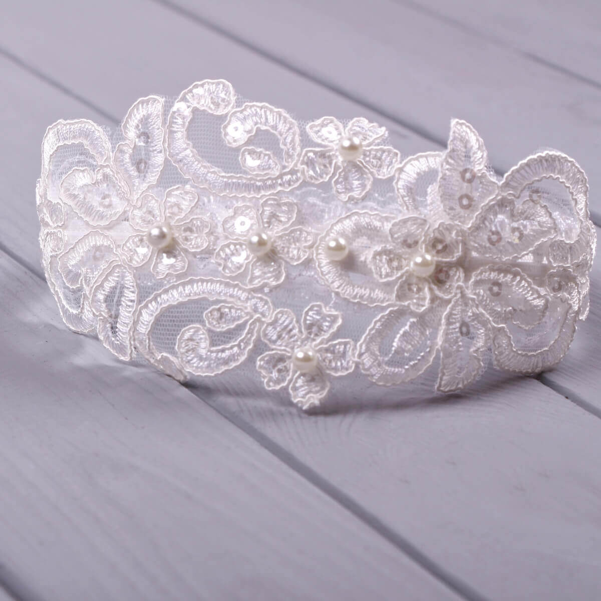  Baby headband with lace and pearls sitting and pearls on a wooden surface