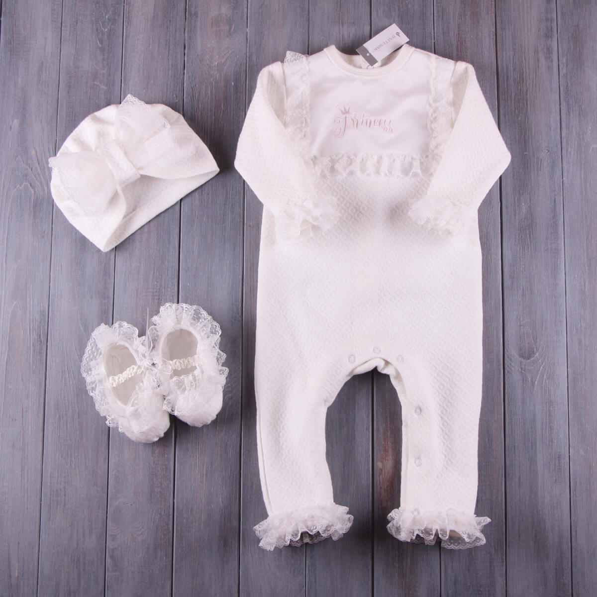 Baptism Romper Set with lace details, white shoes, and hat on a wooden surface