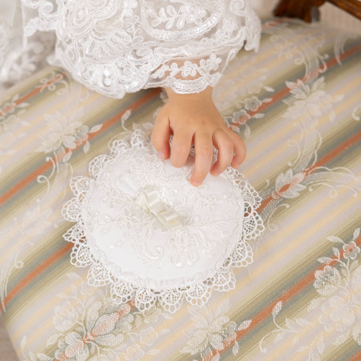Close-up of a hand holding a Ceremony Pillow on a striped fabric background