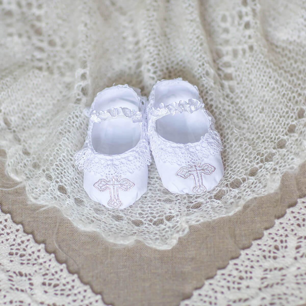 Personalized Baby Keepsake Booties with lace details on a textured fabric background