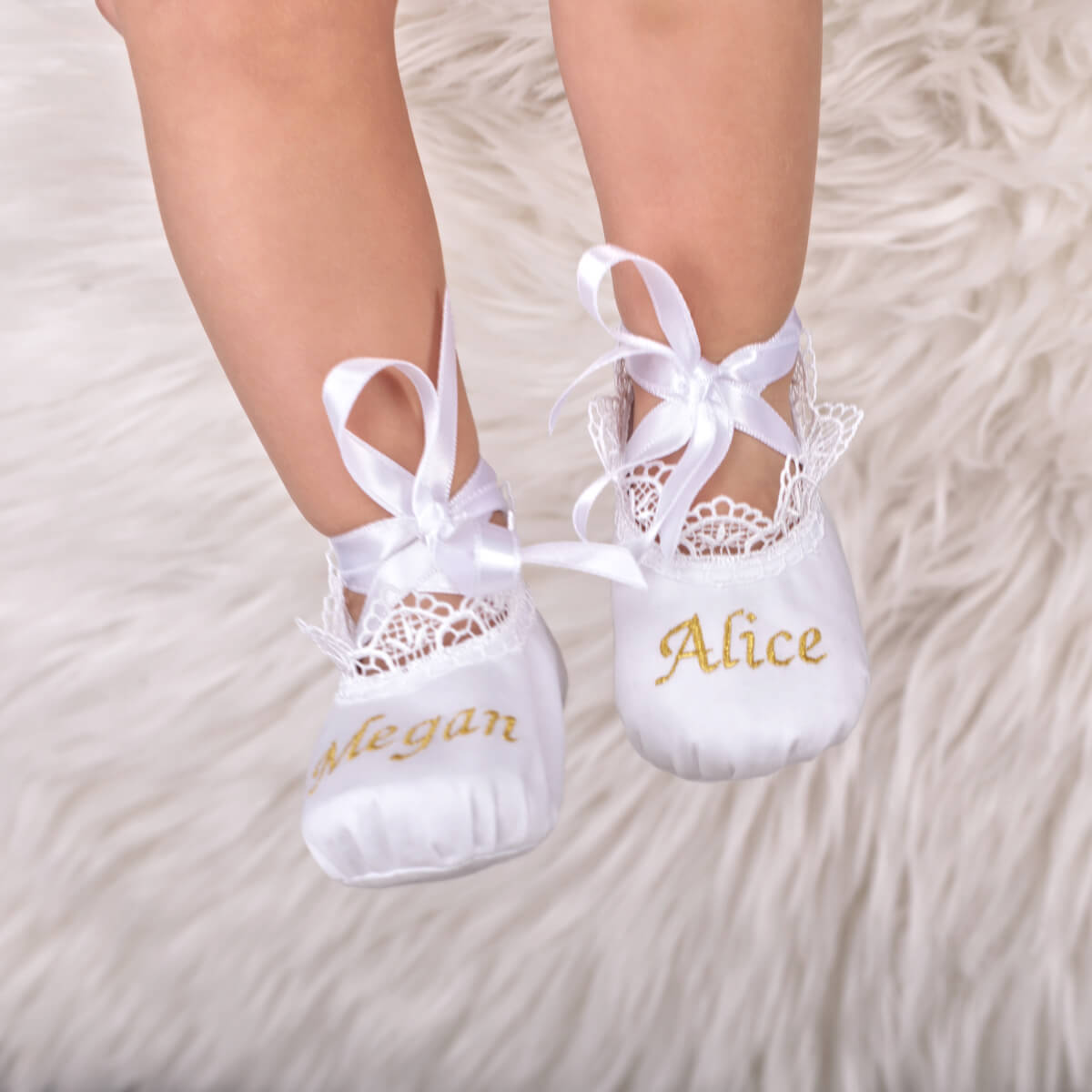 Personalized Baby Keepsake Booties with lace details and embroidered names on a soft surface