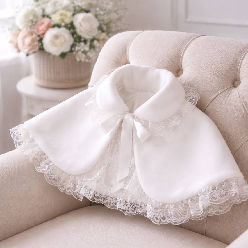 White lace faux fur bolero on a beige sofa with a floral arrangement in the background