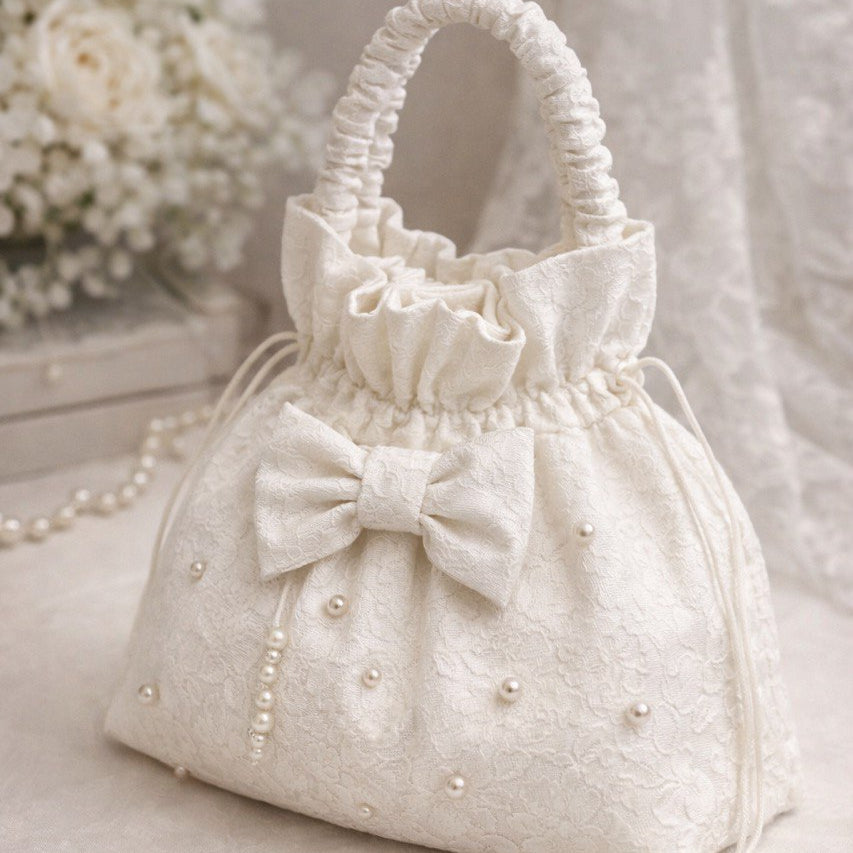 Ivory handbag with a bow and pearl details on a light background