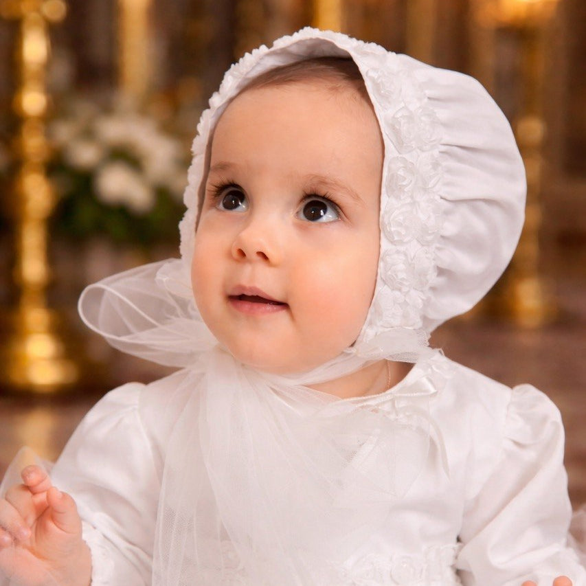 Baby in a white dress with a bonnet in a church setting