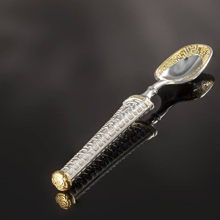 Decorative spoon with gold and silver accents on a black background