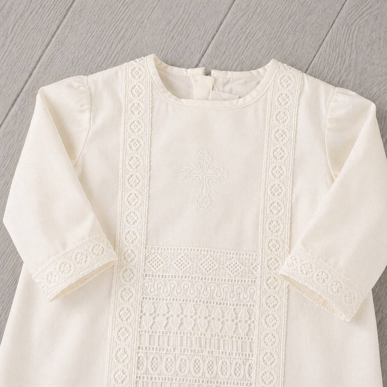 White embroidered boy baptism outfit on a wooden surface