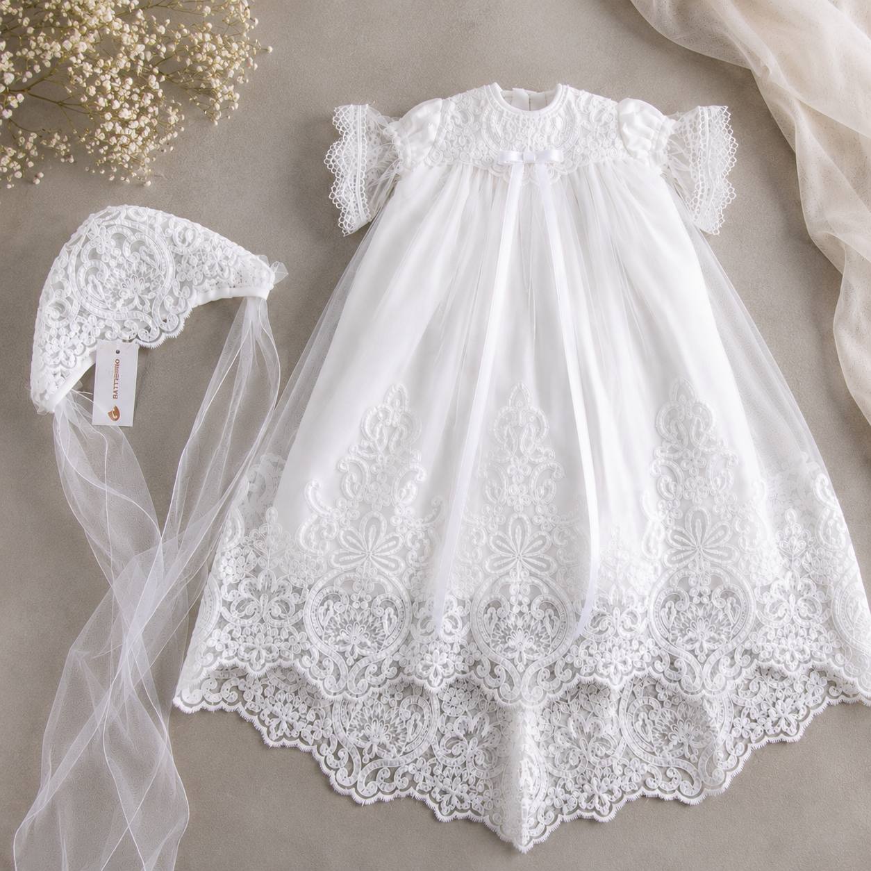 White lace baby baptism dress with matching bonnet on a neutral background