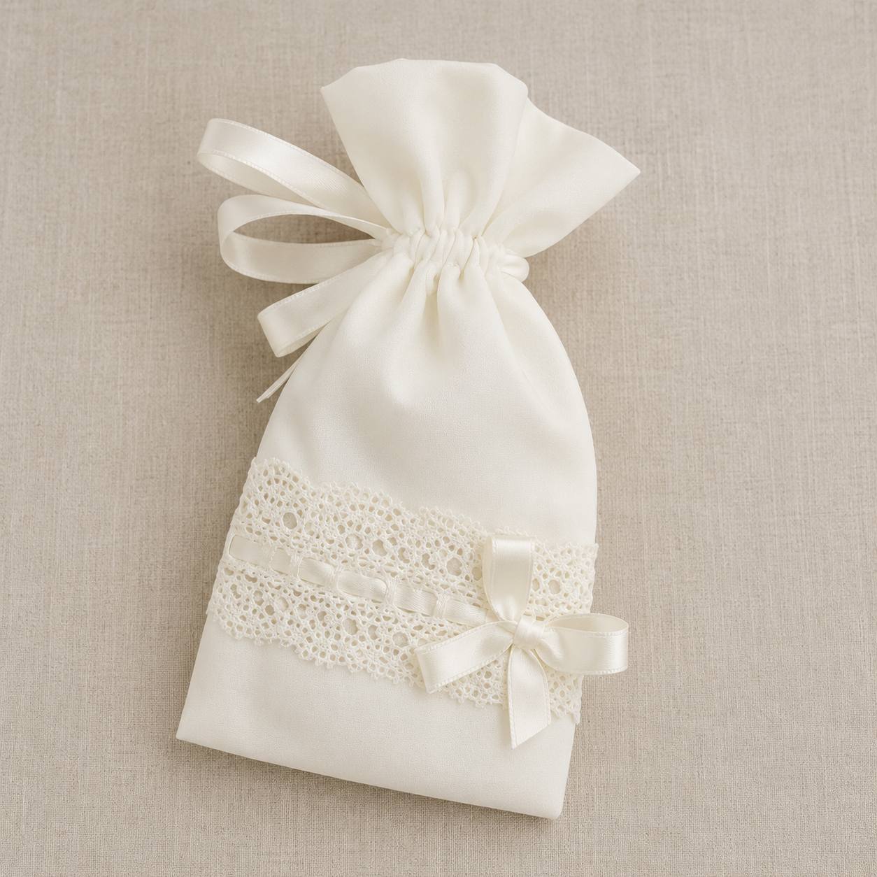 An ivory satin drawstring gift bag with a decorative lace band and a small satin bow, displayed on a neutral beige textured fabric background.