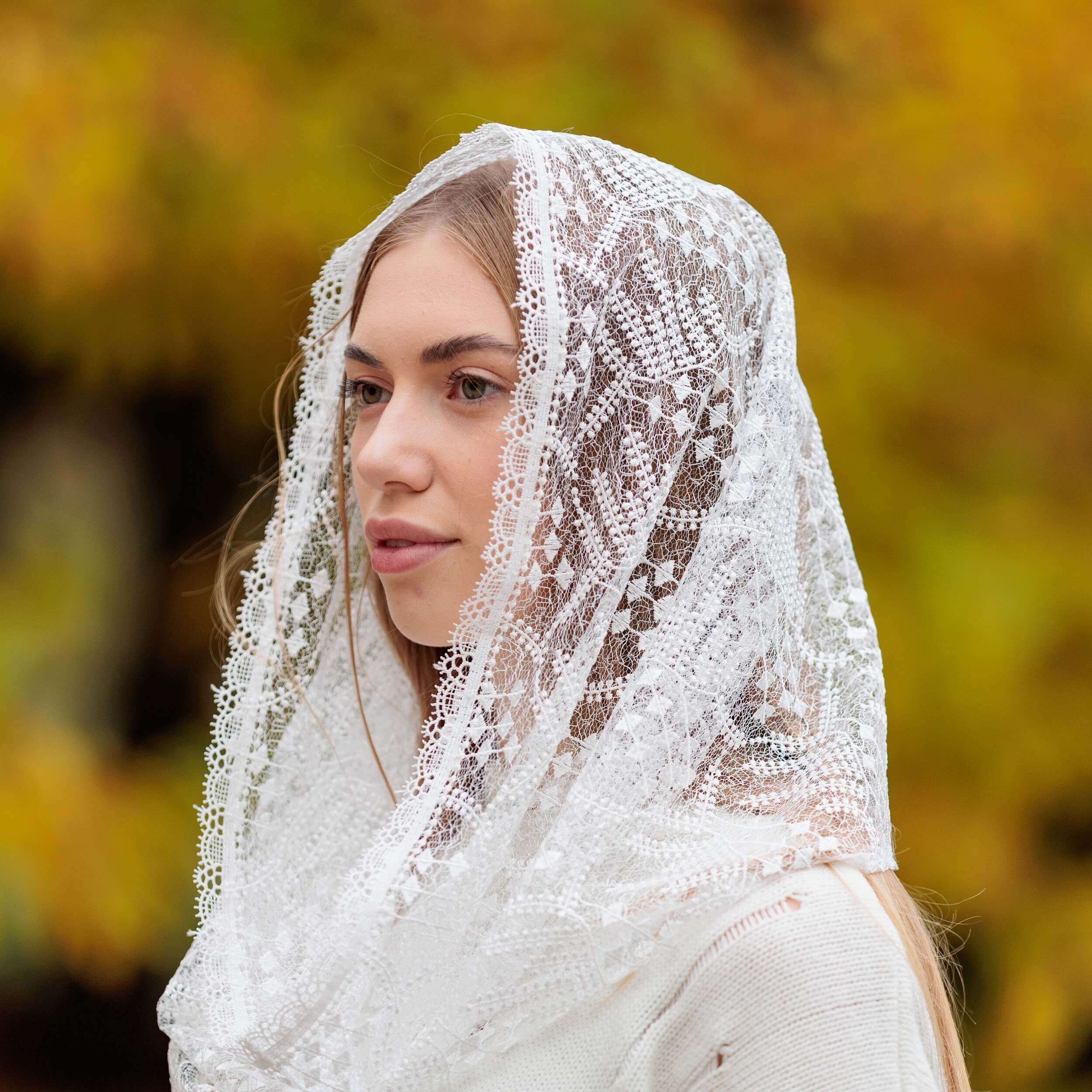 Woman wearing a Catholic Infinity Veil with a blurred autumn background