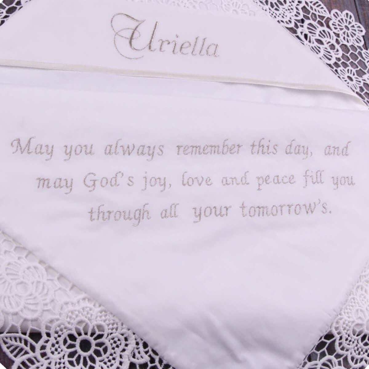 Embroidered praying on a white baptism blanket with lace details