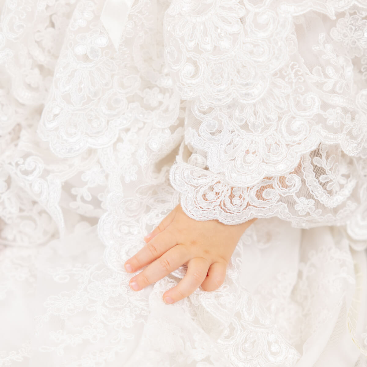 Close-up of a hand in a white lace christening gown 