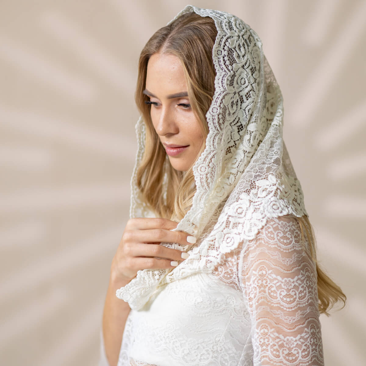 Woman wearing a Catholic Infinity Veil  against a beige background