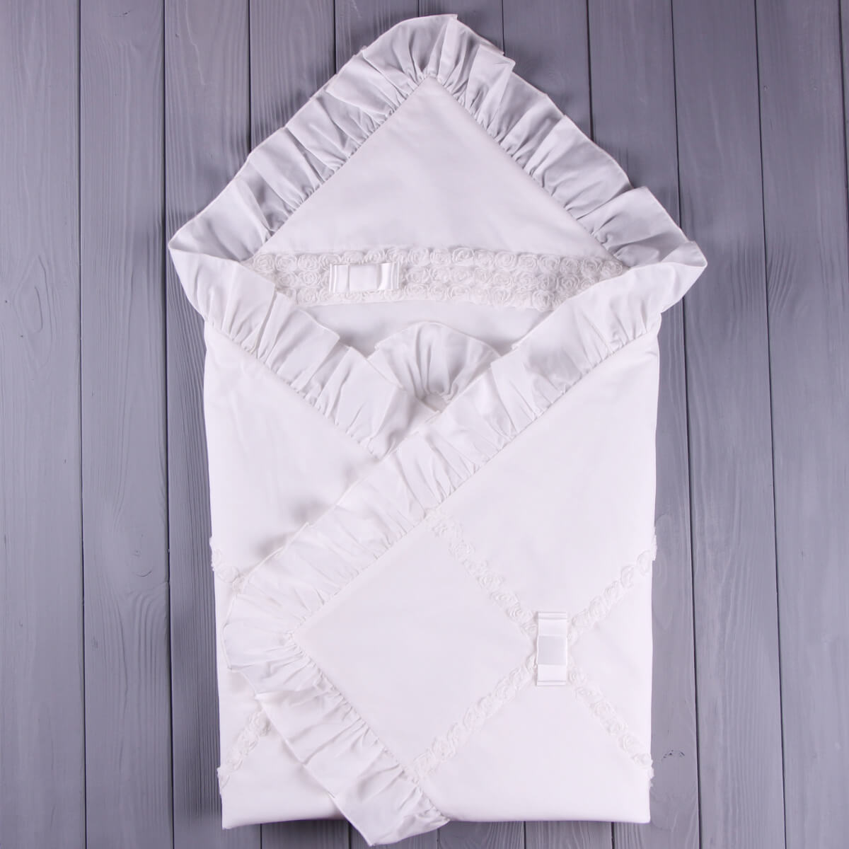 White baby blanket with ruffled edges on a wooden surface