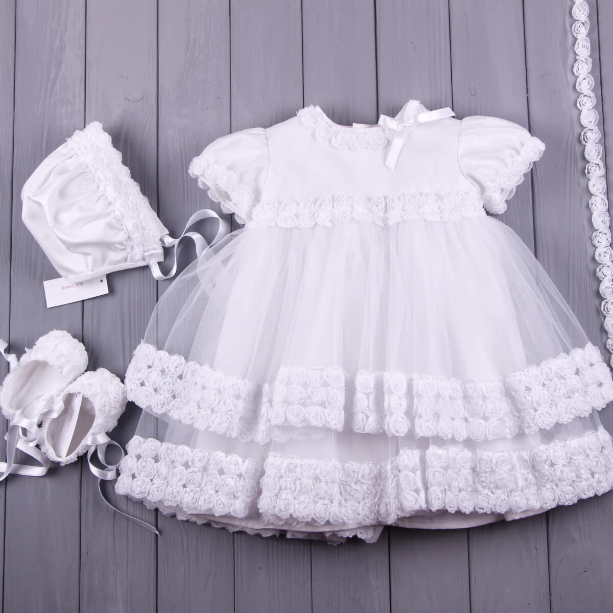 White baby dress with matching Vintage Baptism Bonnet and booties on a wooden surface