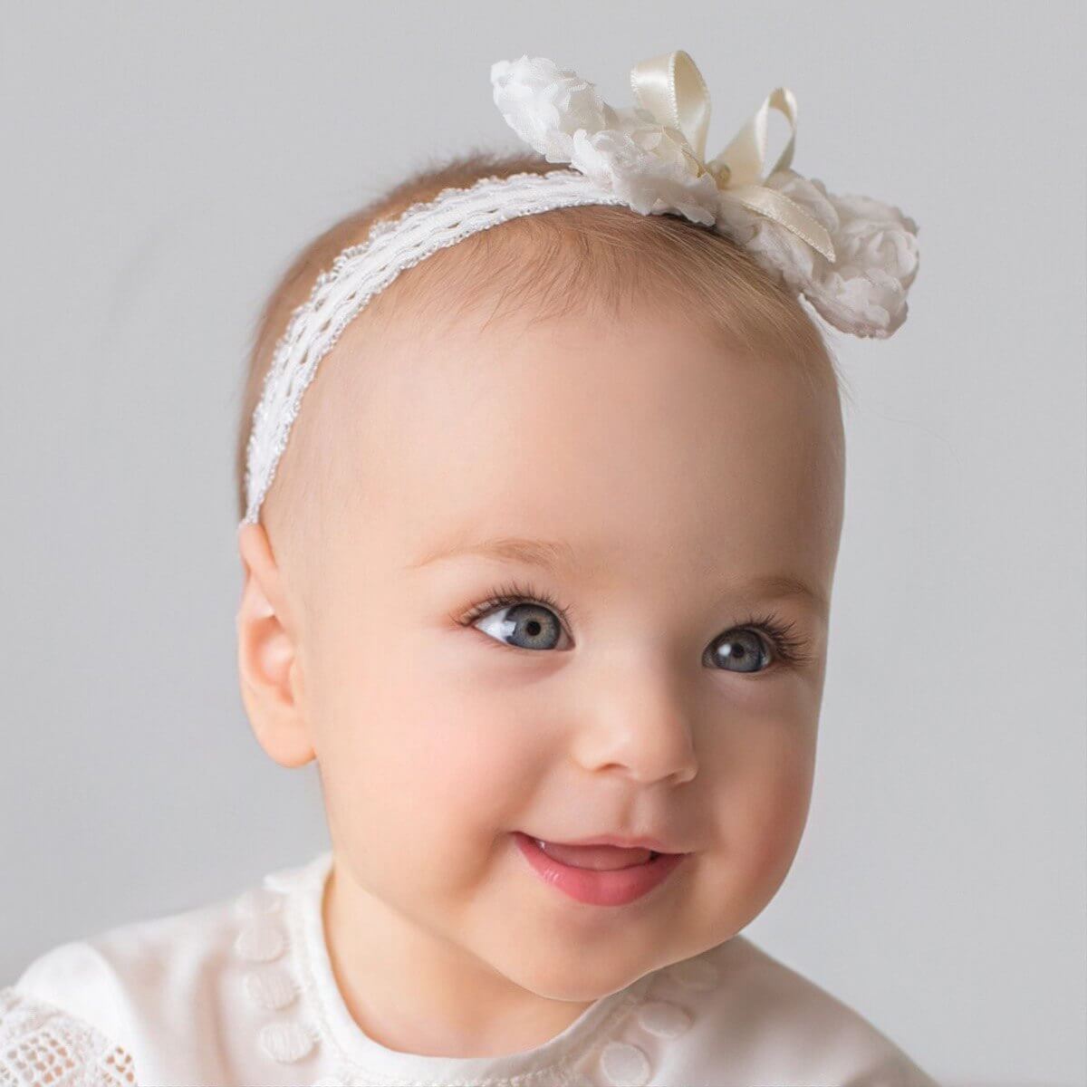 Girl wearing baby headband with bow against a gray background