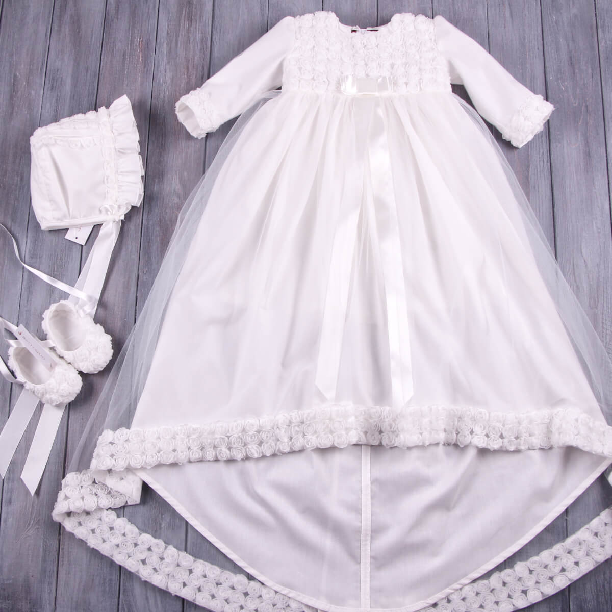 Lace Christening Gown with bonnet and shoes on a wooden surface