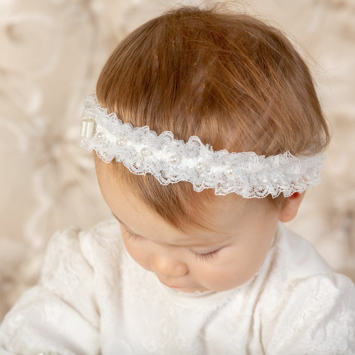 Girl wearing the baby headband with pearls against a soft beige background