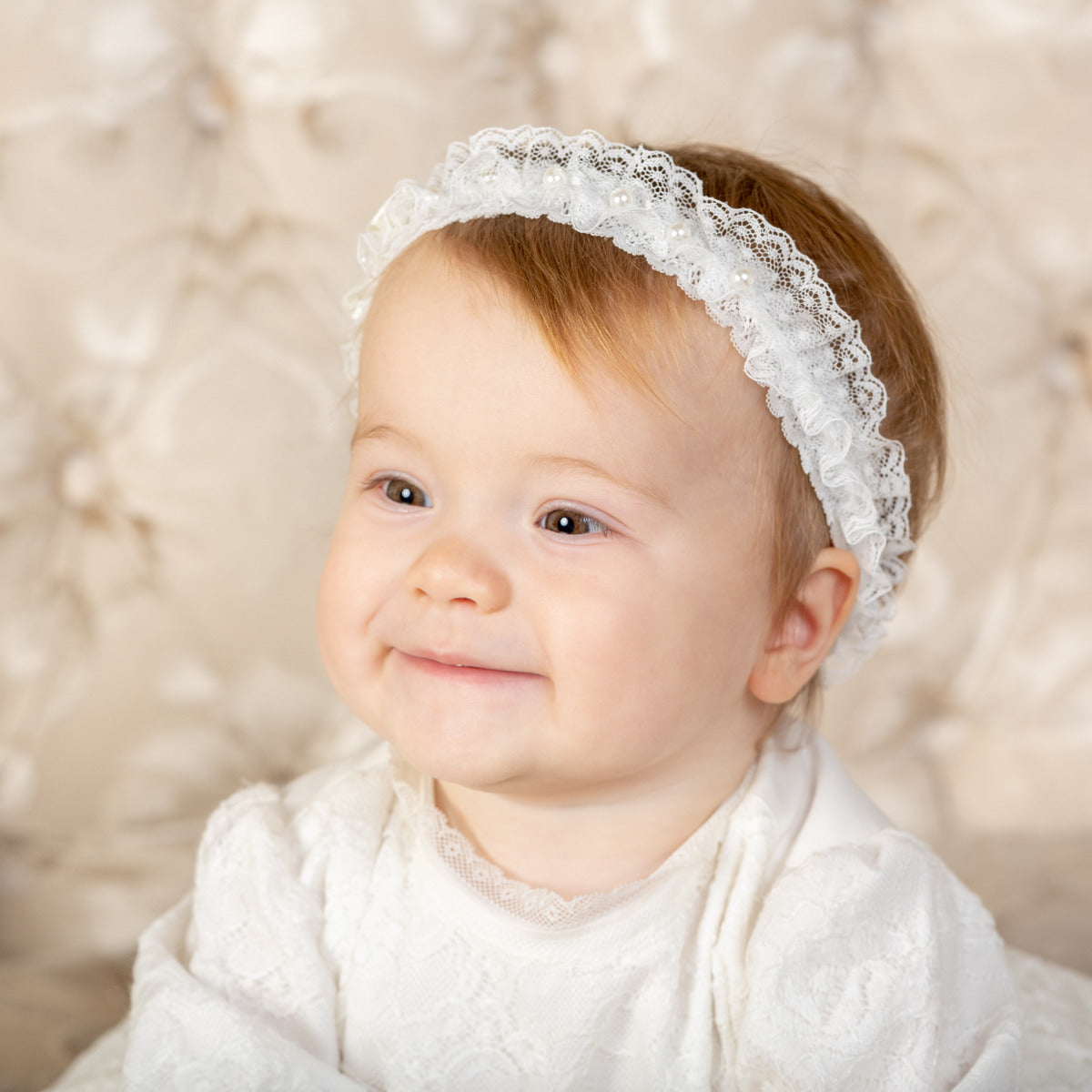Girl wearing the baby headband and white outfit against a soft, blurred background