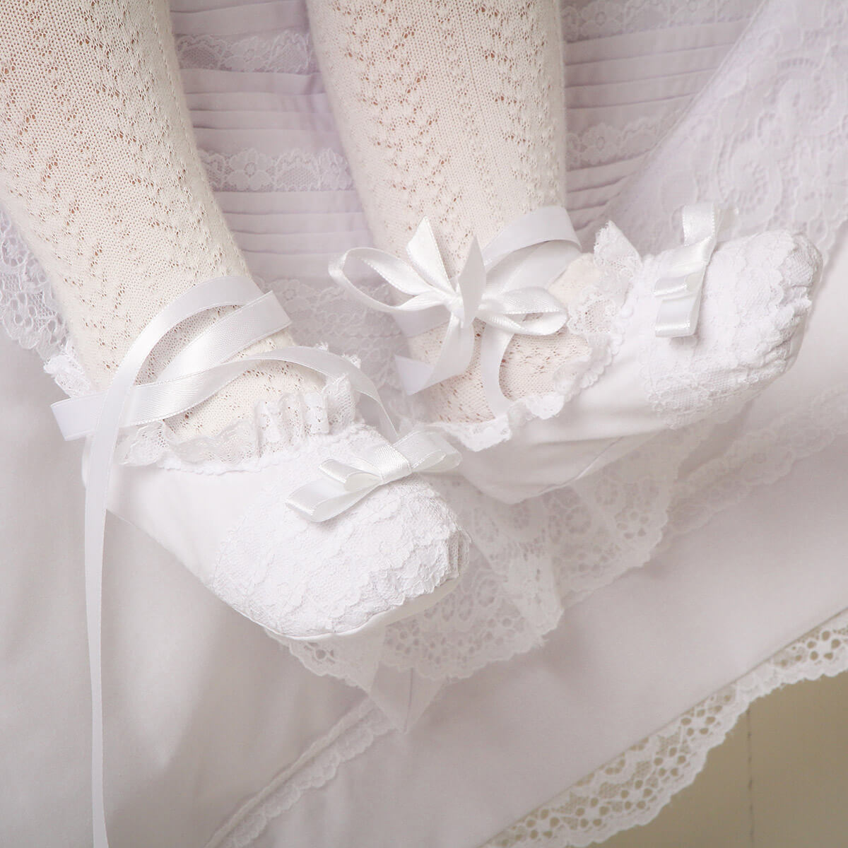 Close-up of a Christening Booties with ribbons and floral details.