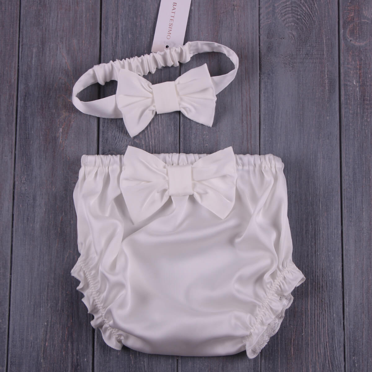 Baby Keepsake Bloomers and headband with bow on a wooden surface