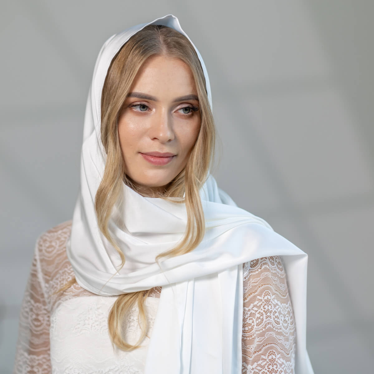 Woman wearing a Church Mantilla and lace garment against a gray background