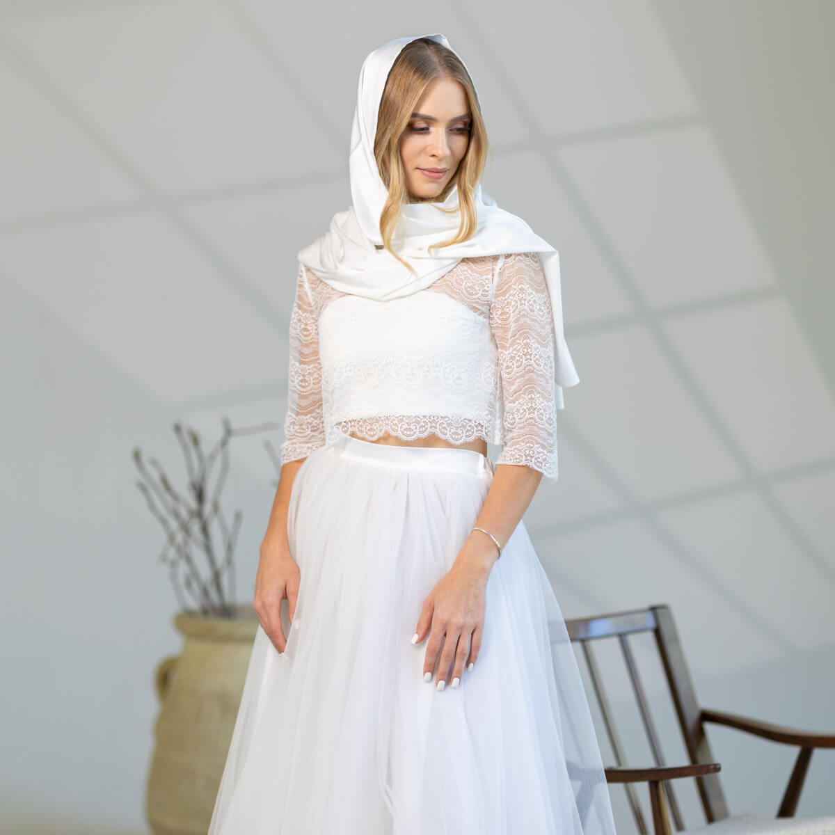 Woman wearing a white lace dress and Church Mantilla in a minimalistic room.