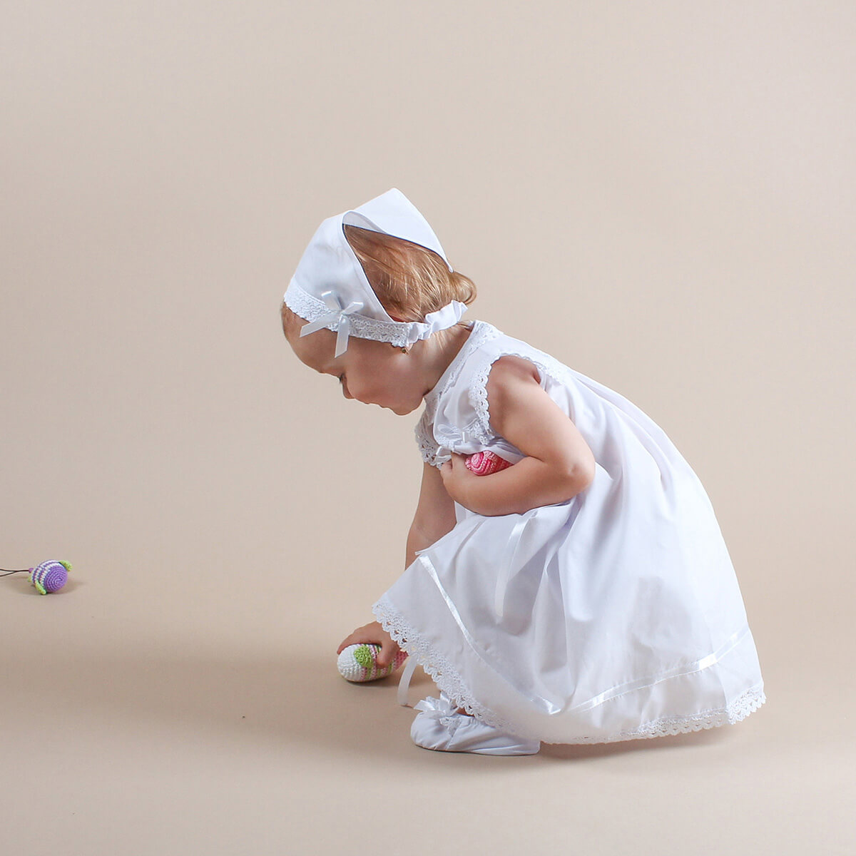 Young girl in a Summer Baptism Dress Set for Girl and headband on a beige background