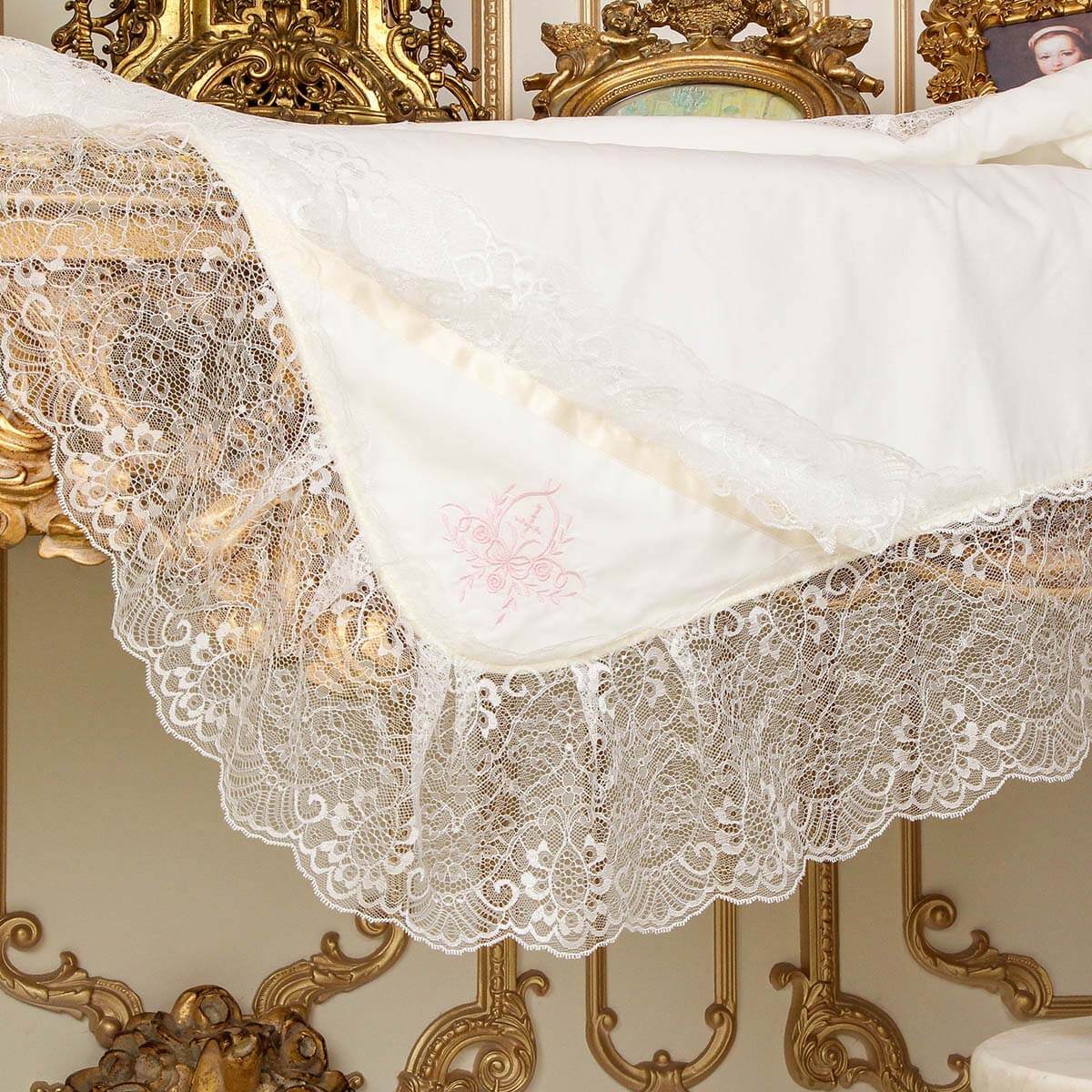 Lace baptism blanket on a decorative table with ornate gold frame