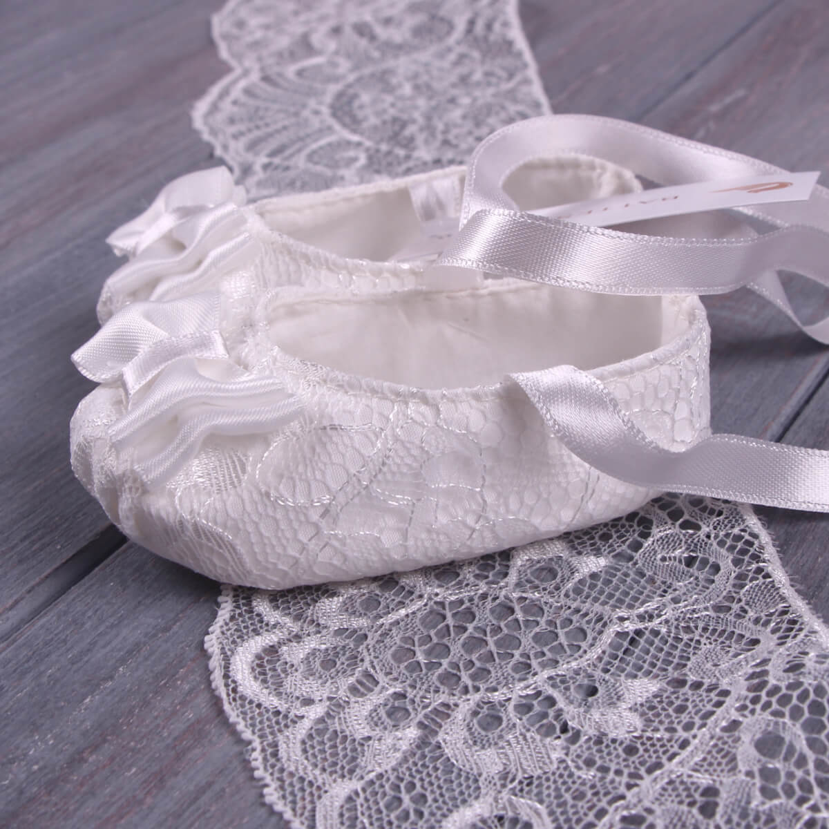 Christening Booties with ribbons on a wooden surface