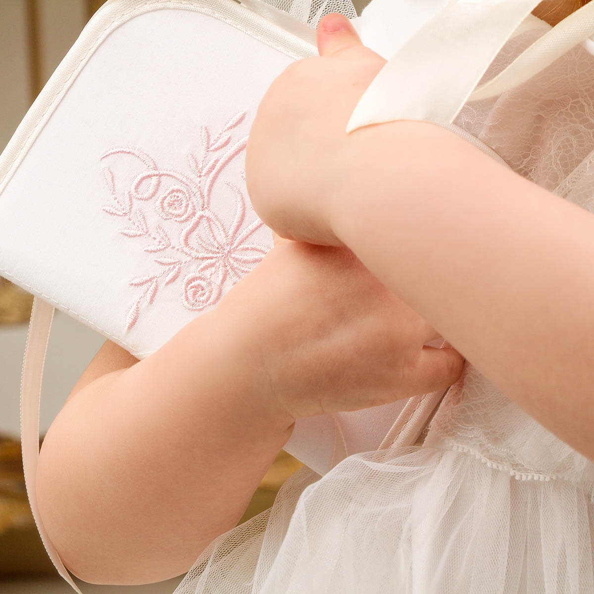 Close-up of a child's hands holding a Baby Baptism Keepsake Box with floral embroidery.