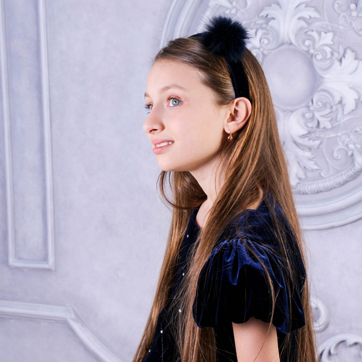 Young girl with a decorative headband against an ornate white wall