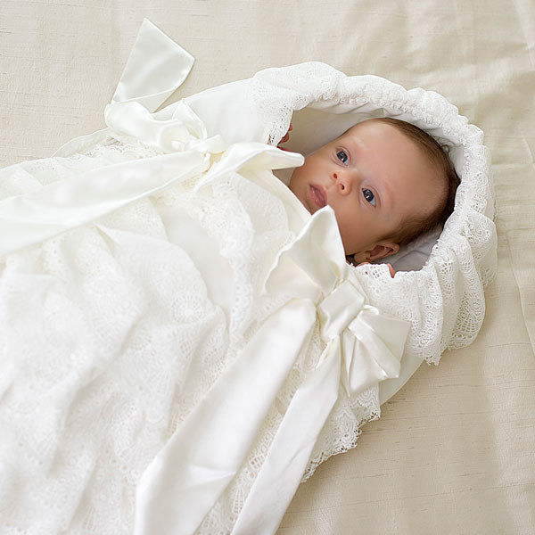 Newborn baby wrapped in a Newborn Sleep Sack on a light beige surface