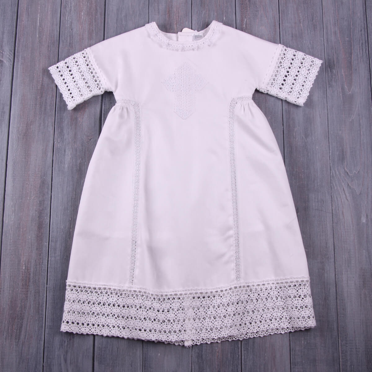 Baptism Gown with lace details on a wooden surface
