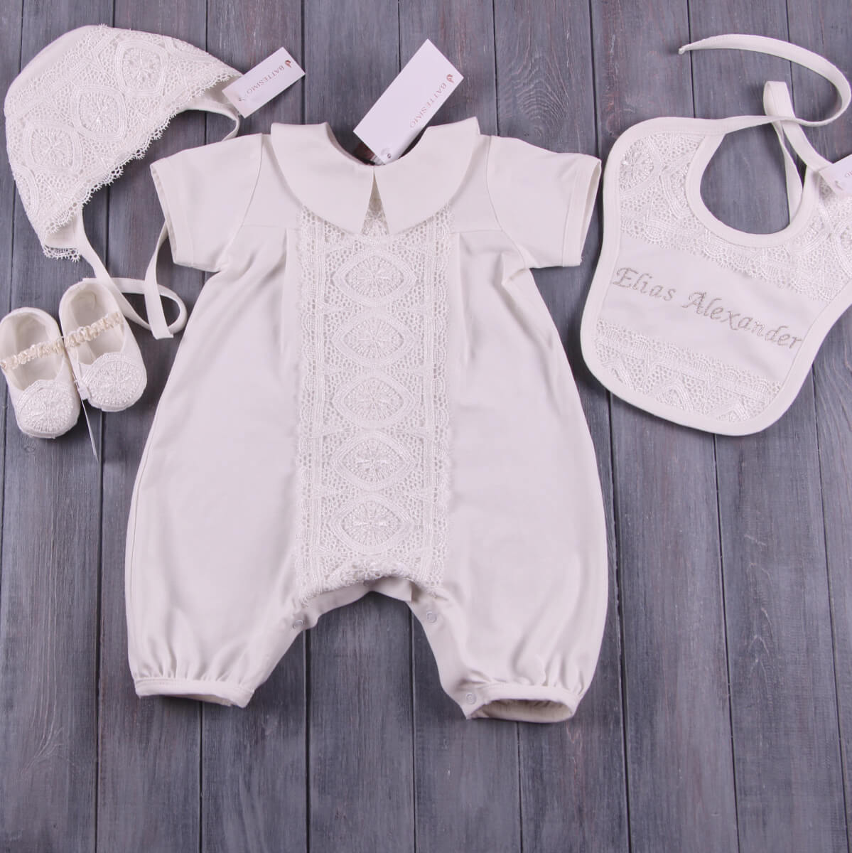 Handmade Baptism Outfit with romper, hat, shoes, and bib on a wooden surface