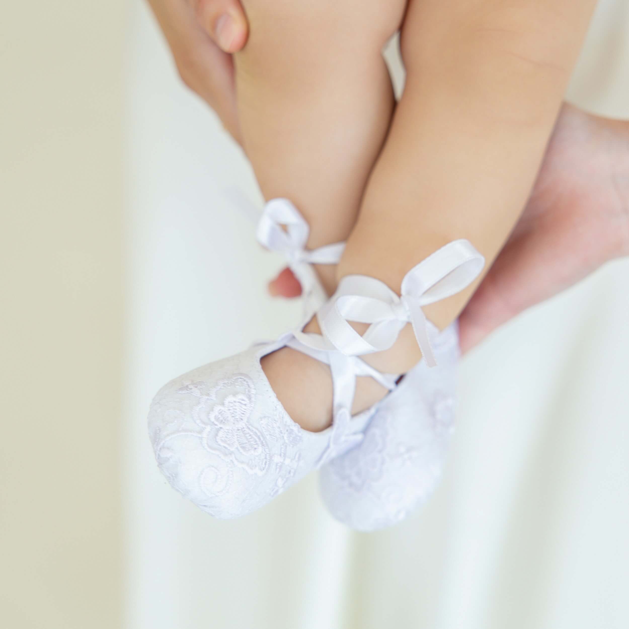 Christening Booties with lace details on a light background