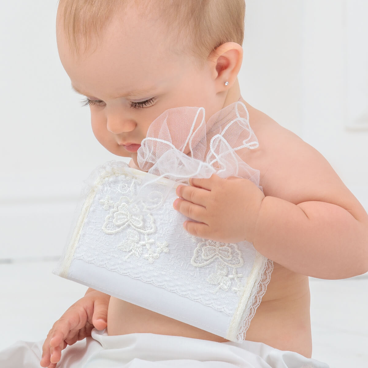 Baby holding a First Curl Keepsake Box against a plain background