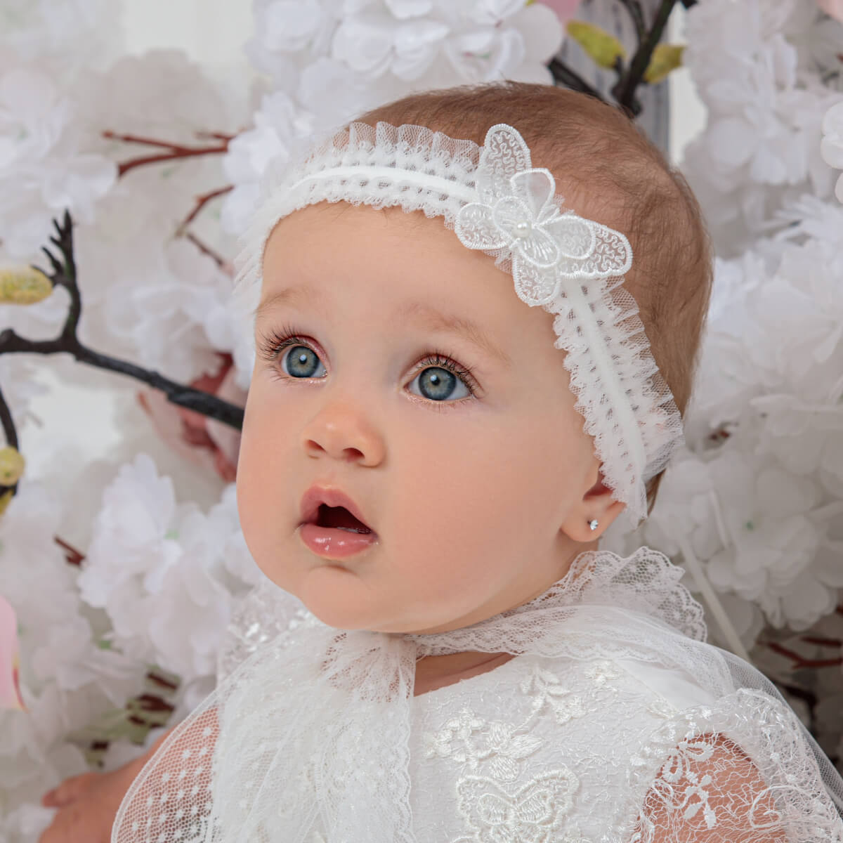 Baby wearing  the baby headband with a butterfly design against a floral background
