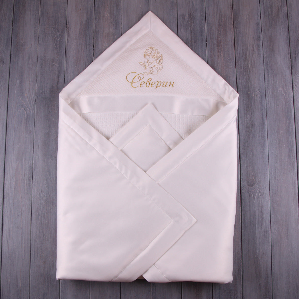 Baptism blanket with embroidered text on a wooden surface