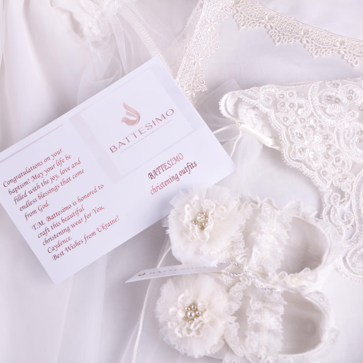Battesimo Christening Booties with card on a white lace background