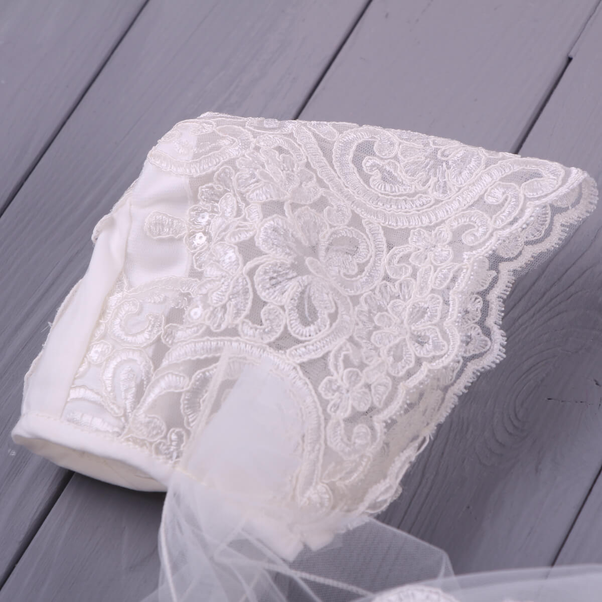 White lace bonnet of Lace Christening Outfit on a wooden surface