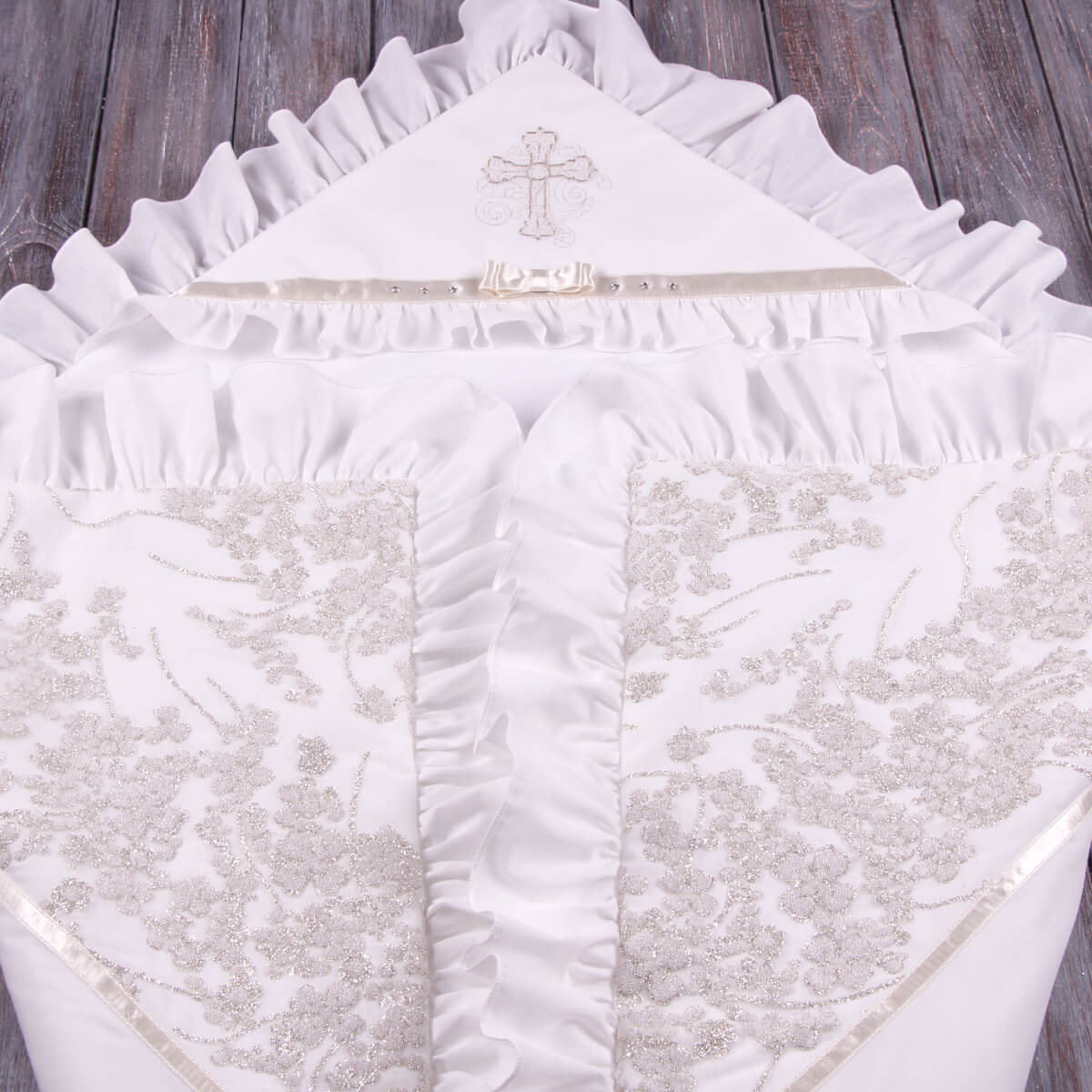 White embroidered blanket with a cross design on a wooden surface