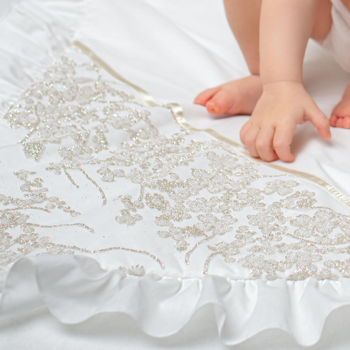 Close-up of a baby's feet on a white crib sheet with decorative patterns