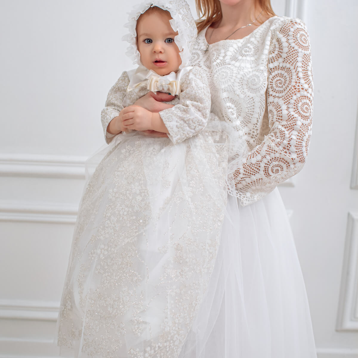 Two children in matching  Christening Gown for Girls standing against a white background