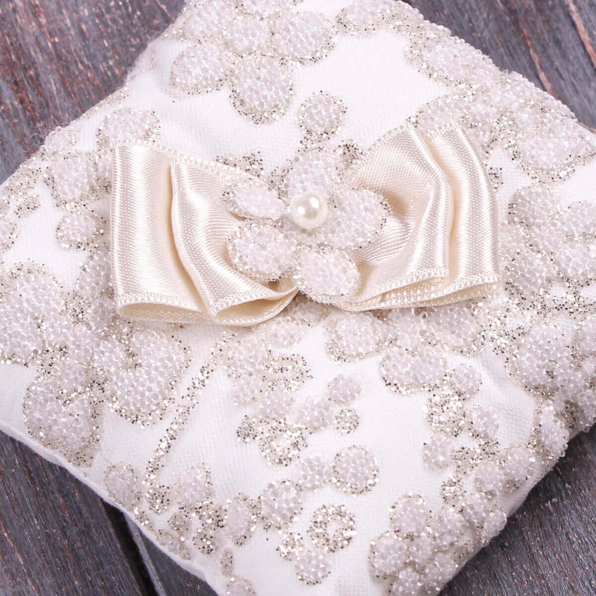 Christening Ceremony Pillow with a floral design and pearl embellishments on a wooden surface